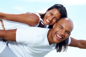 Closeup portrait of a joyful young couple on holiday having fun against sky